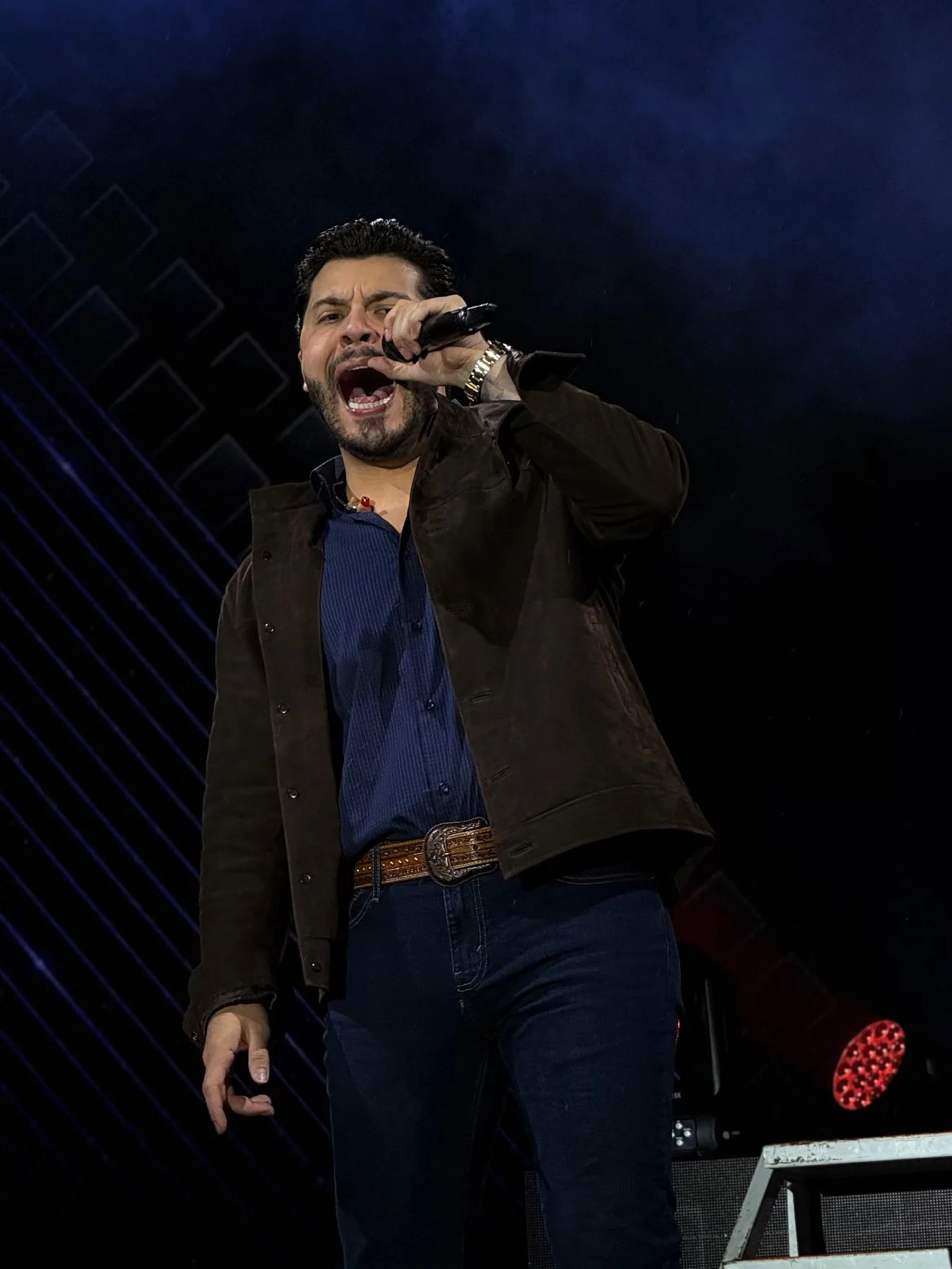 Cantor de camisa escura em apresentação no palco.