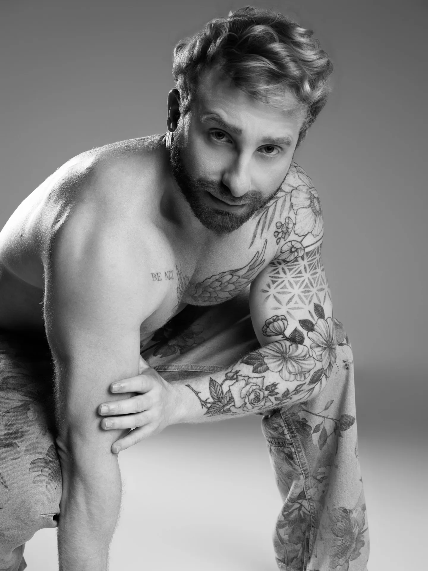 Retrato em preto e branco de homem com braços tatuados.