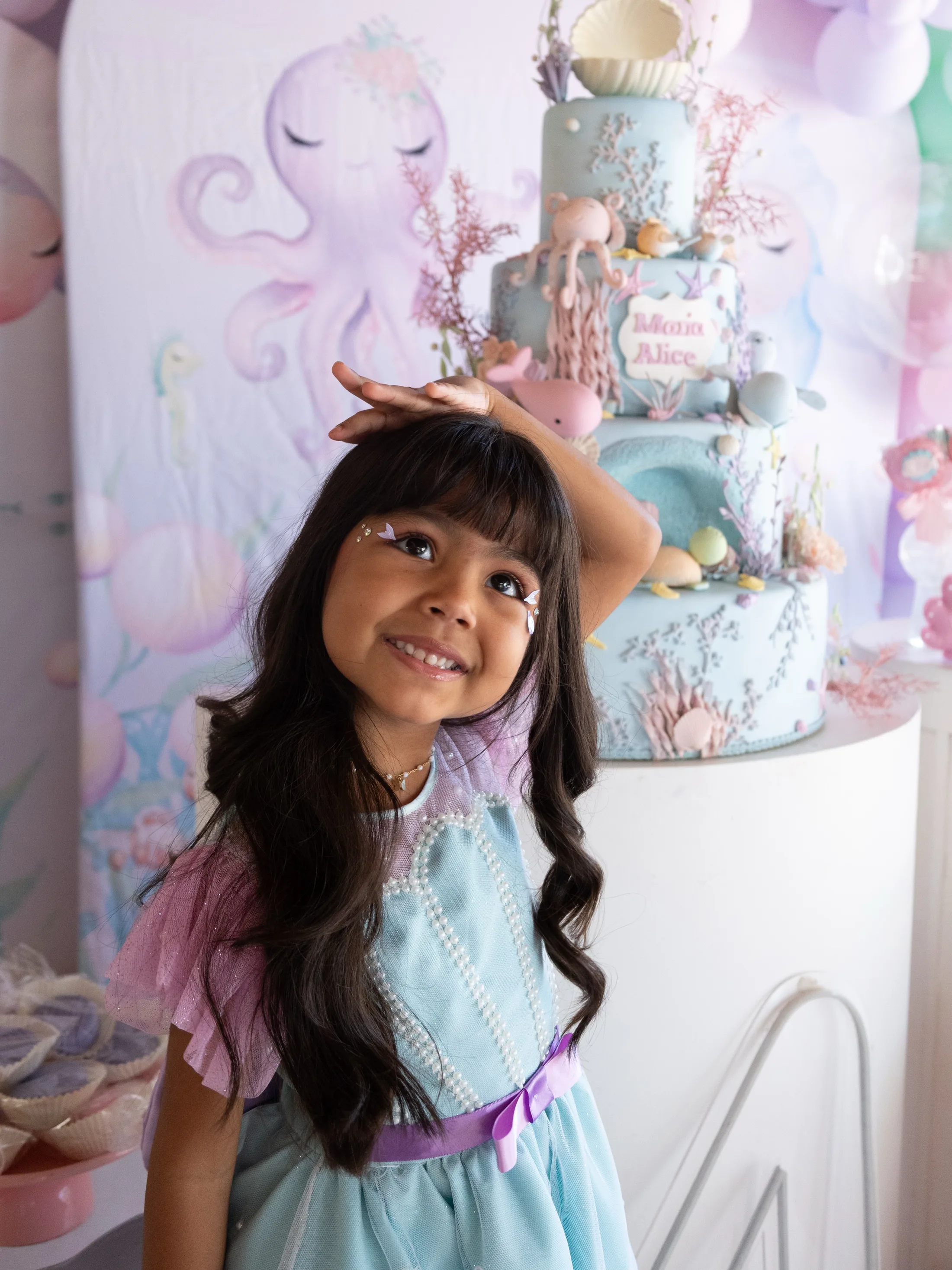 Menina sorrindo diante de uma decoração de aniversário.