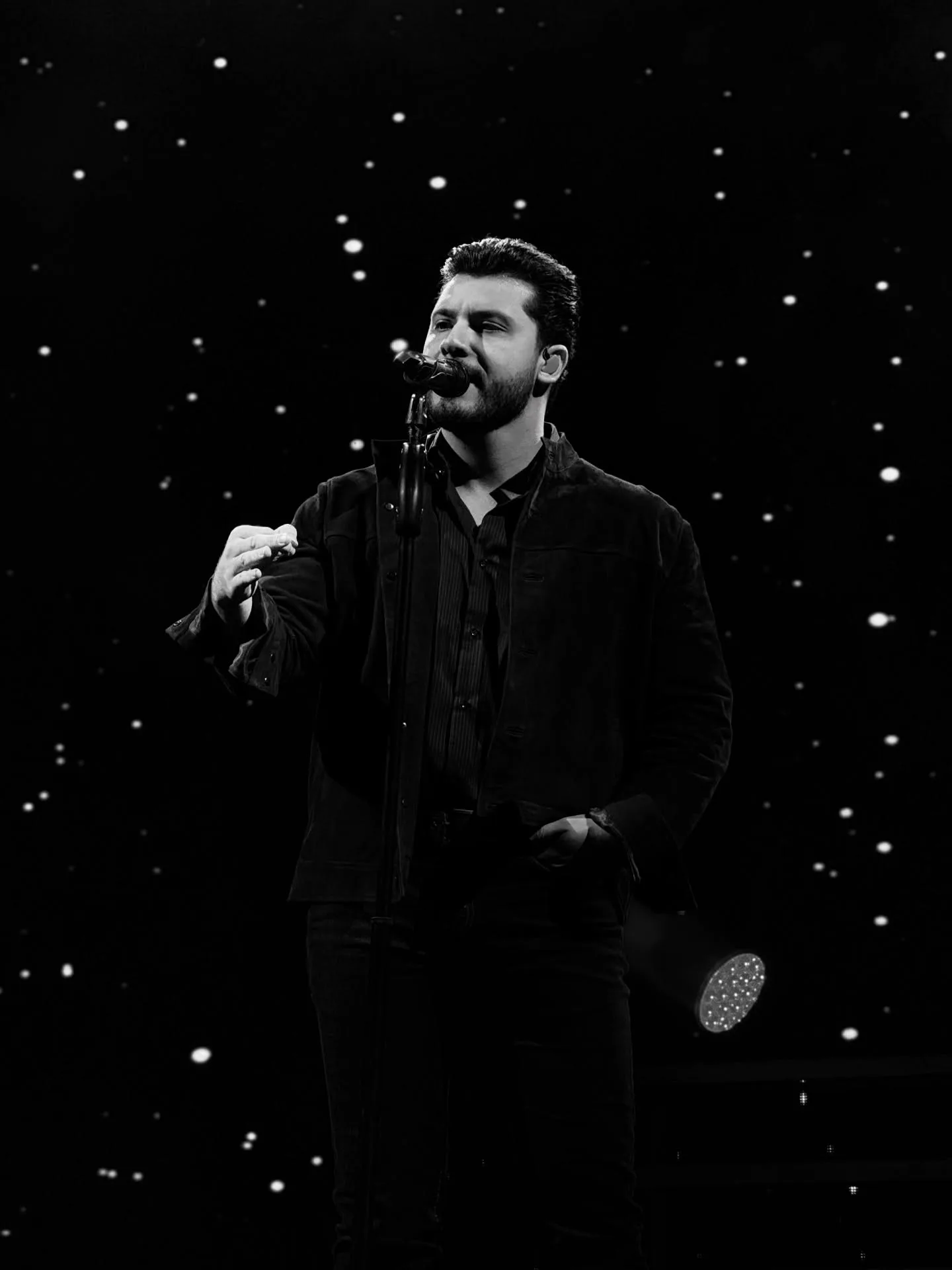 Retrato em preto e branco de cantor durante apresentação.