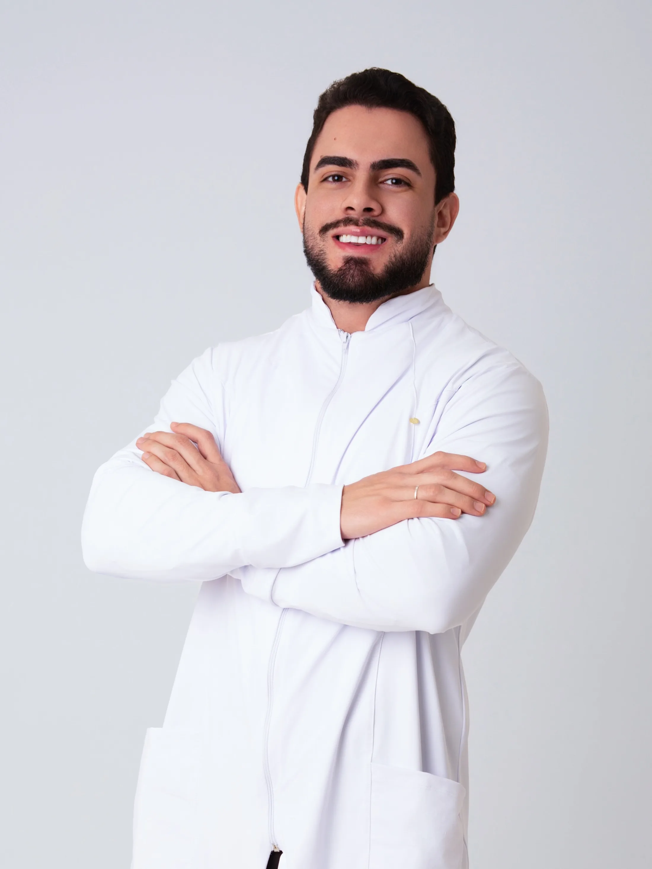 Homem de camisa branca com braços cruzados em estúdio.