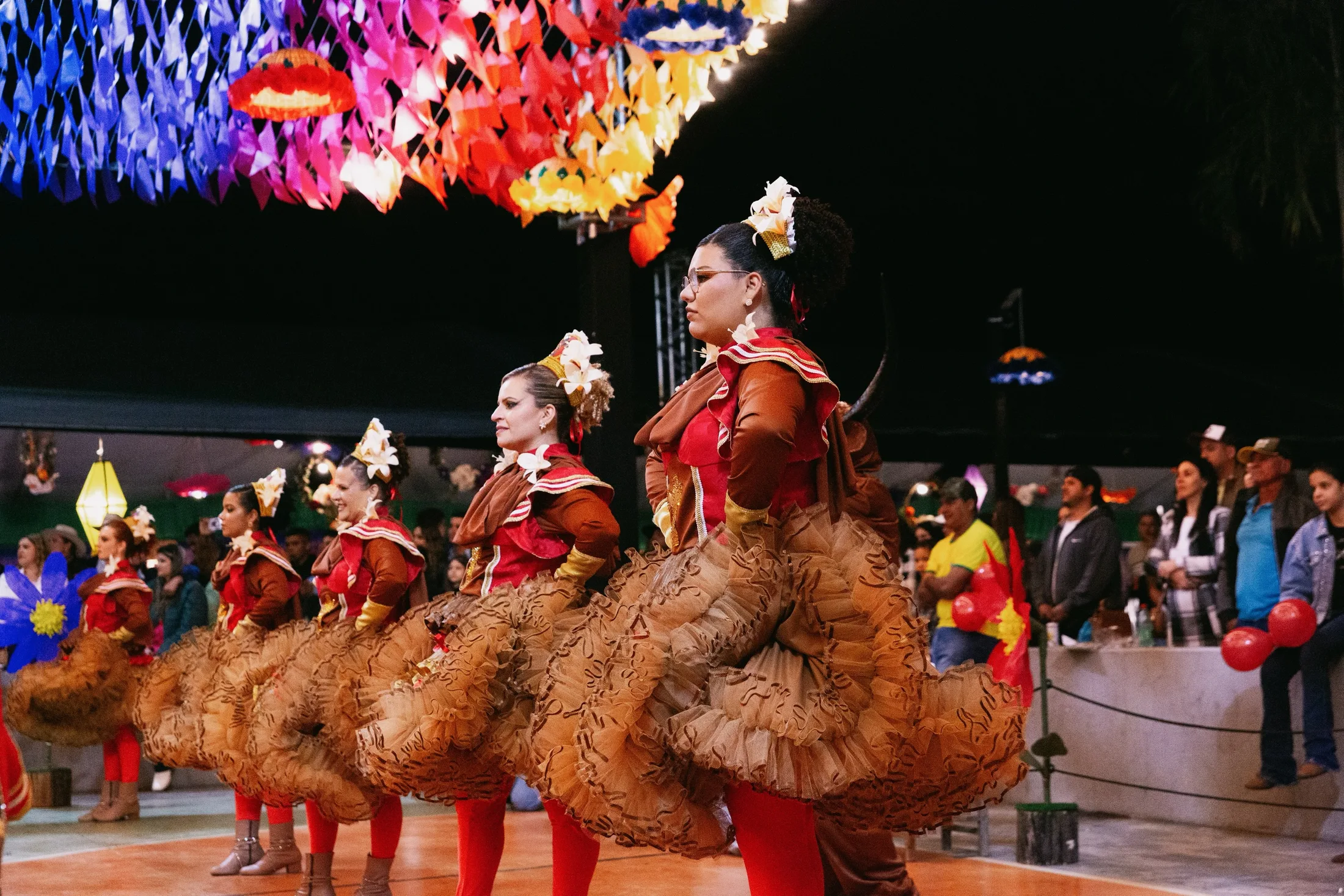 Grupo de dança junina em apresentação com bandeirinhas coloridas.