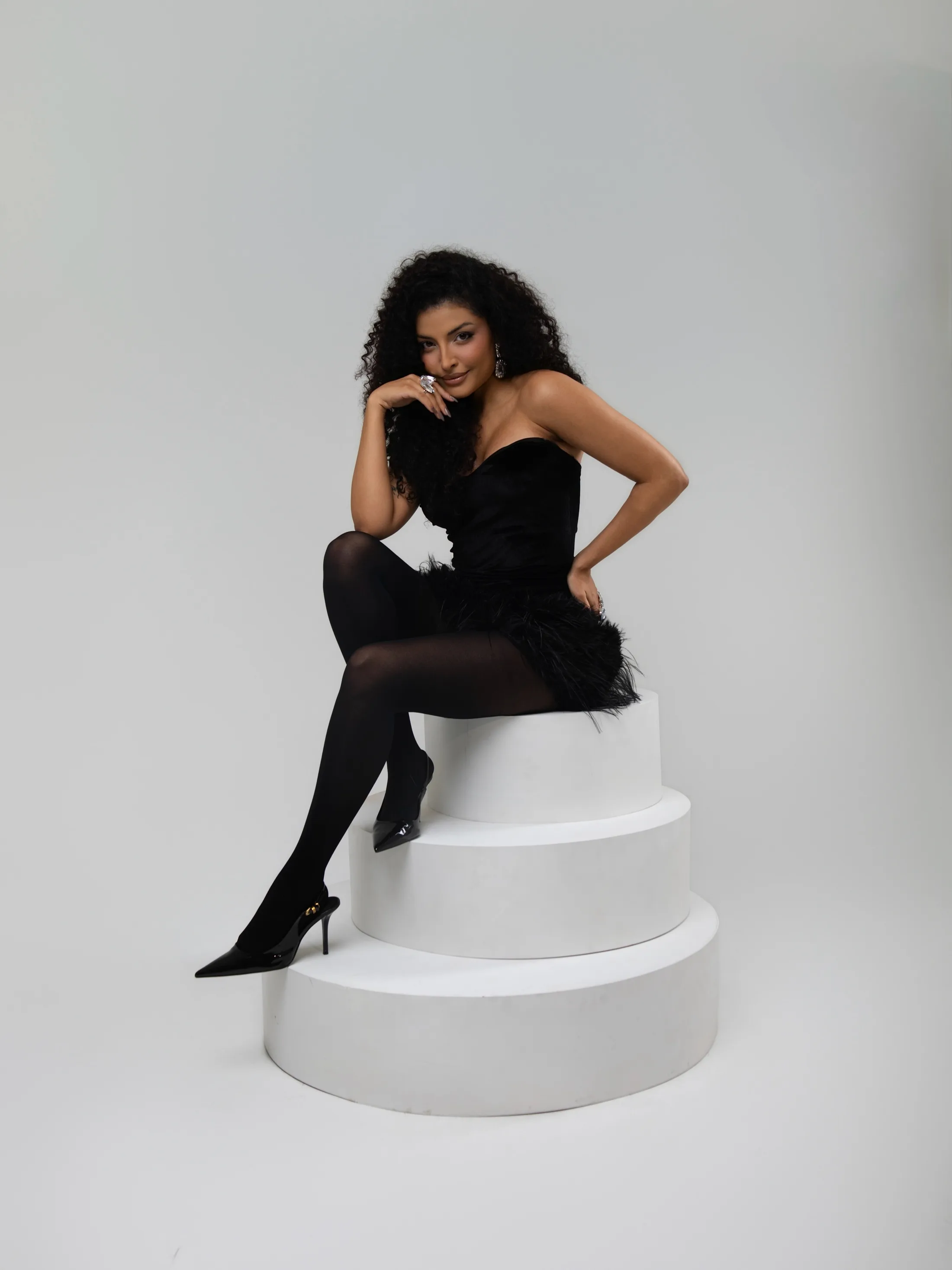 Mulher de roupa preta sentada sobre um cilindro branco.