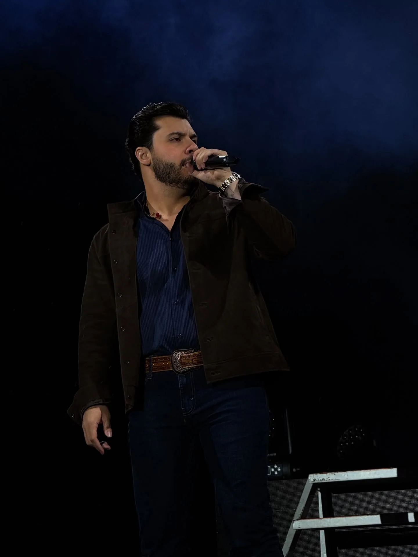 Cantor no palco sob luz azul e fundo escuro.